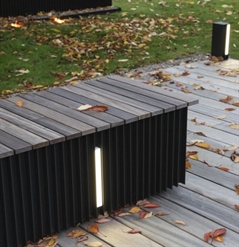 black aluminum seating block with an led light integrated on the side placed on a patio with leaves