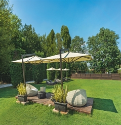 Several beige side arm parasols shading lounging areas in a big green space