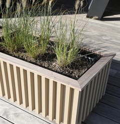 close up of a wooden style aluminum planter box potted with small plants outside in the daytime
