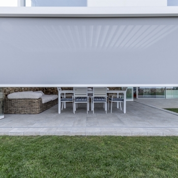 Gray screen drawn half way down that is integrated into a retractable pergola