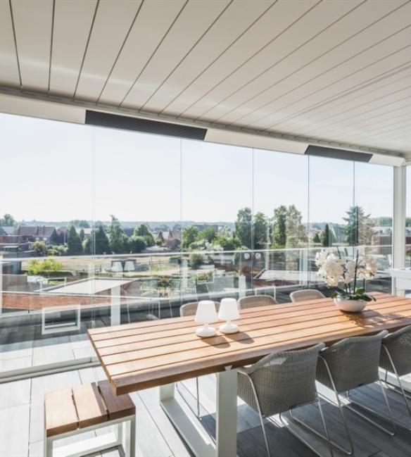 Heaters integrated into the roof beams of a white retractable pergola over an outdoor dining patio