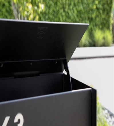close up of a black aluminum mailbox opening and its spring mechanism