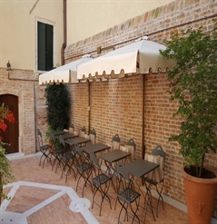Cream parasols with brown trim along a brick wall of a restaurant over seating area