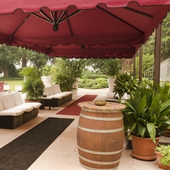 Two large red parasols with decorative trim over outdoor seating area 