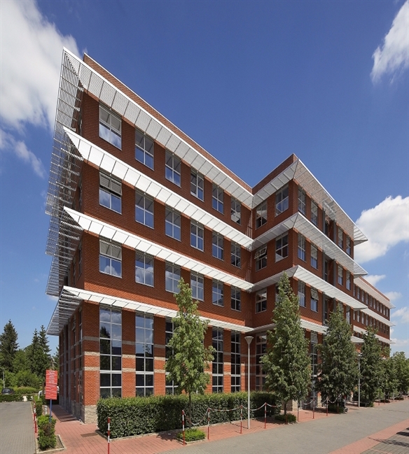 Horizontal brise-soleil Sunclips continues above windows of a three storey brick building