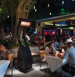 portable standing heater turned on at night placed in an outdoor patio of a restaurant