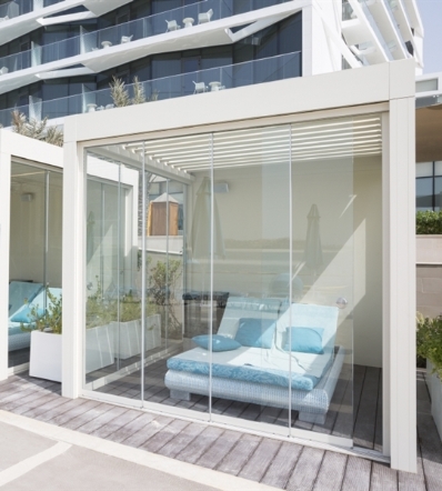 Glass panels enclose the side of a white aluminum hotel cabana  