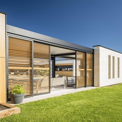 black aluminum sliding panels with brown wooden style louvres that tilt installed on a black pergola