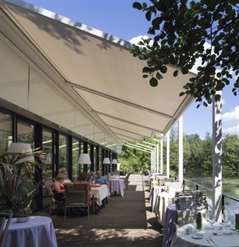 a white pvc pergola that retracts installed as a patio cover for a restaurant sitting over the water
