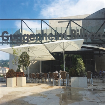 White parasols over outdoor café seating in front of a museum