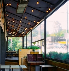 view from the inside out from a restaurant patio enclosed with clear pvc screens and lighting above