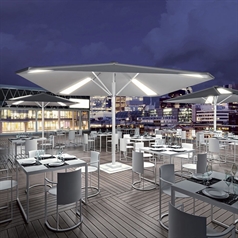 white patio umbrellas spread across a large outdoor patio at night with integrated lighting