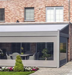 a grey pvc pergola attached to a brick home enclosed with screens that have a crystal window in them