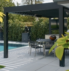black louvred pergola with louvres attached to the facade of a home covering the patio