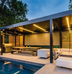 Aluminum pergola louvered over patio poolside with soft LED lights lit 