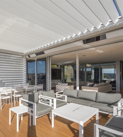 White pergola over outdoor home patio living area with integrated heaters in roof beams