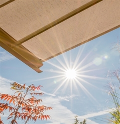 close up of the sun shining at a cream coloured fabric awning