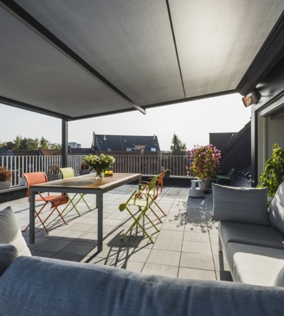 black fabric retractable awning shading from the sun on a rooftop apartment patio