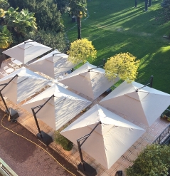 Seven side arm parasols facing each other and covering a large outdoor patio view from above