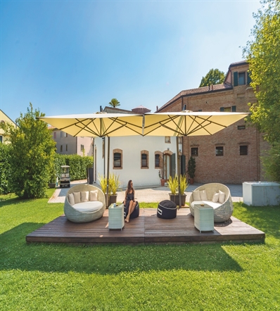 Two beige side arm parasols side by side over a wooden patio area with large loungers