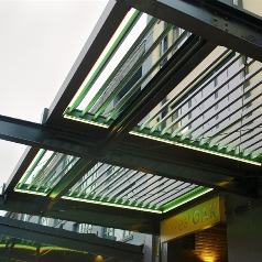 Led lights lite up green beam up and soft white beaming down on retractable pergola roof beams