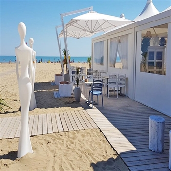 White parasols opened over outdoor dining area on the beach