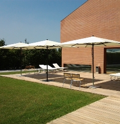 Three centre pole cream parasols shading a backyard patio area on a sunny day