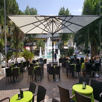 white slim umbrella with a black base covering an outdoor restaurant patio with diners underneath