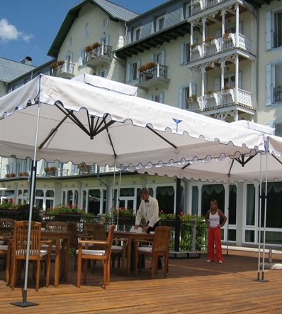 White large parasols with detailed trim over outdoor restaurant seating