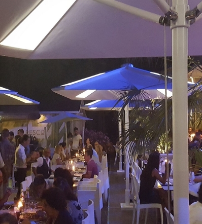 a series of white umbrellas with backlit panels spread across an outdoor area hosting an event