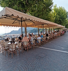 beige umbrellas with a fancy trim covering a street side patio with diners underneath