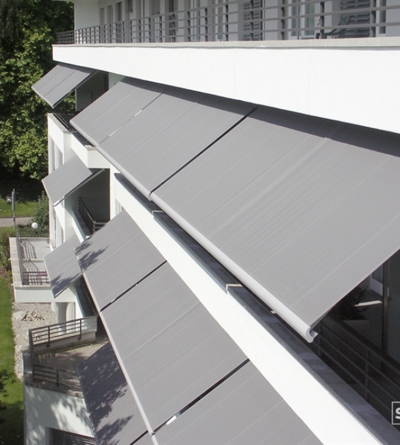 Ariel view of Grey awning attached to building and extended over apartments for shade