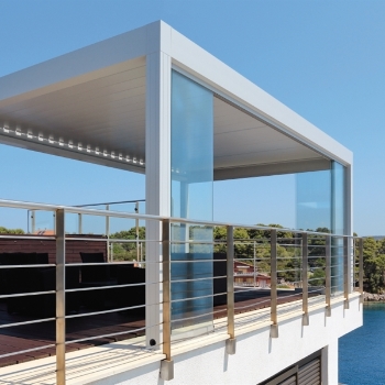 Glass panel sliding side doors integrated into a white aluminum pergola on a elevated patio space