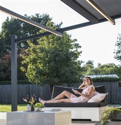 a lady sitting underneath a pvc retractable pergola with LED lighting strips, using the remote