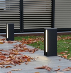 black aluminum led lighting features along the walkway of a home with orange leaves on the grass