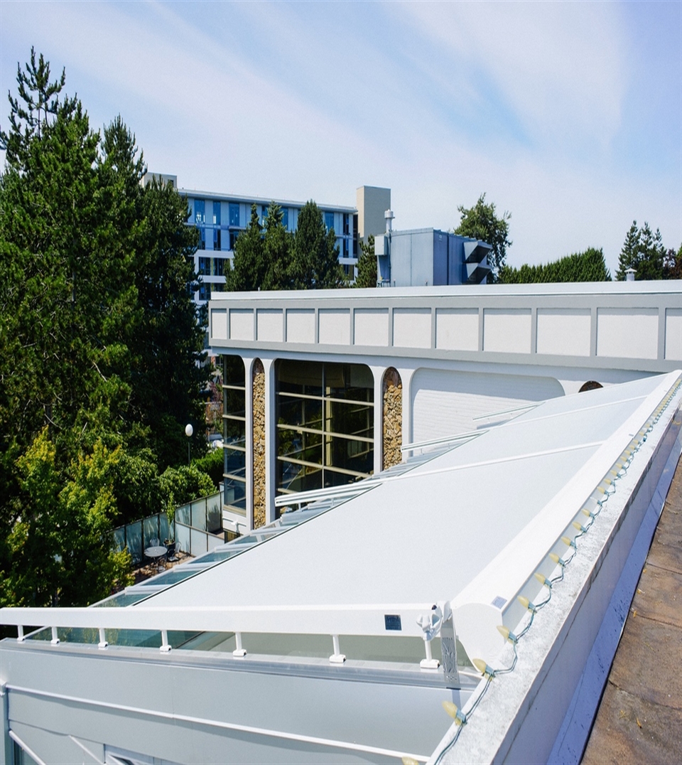 white external roller blind installed on top of a large glass awning of a bistro