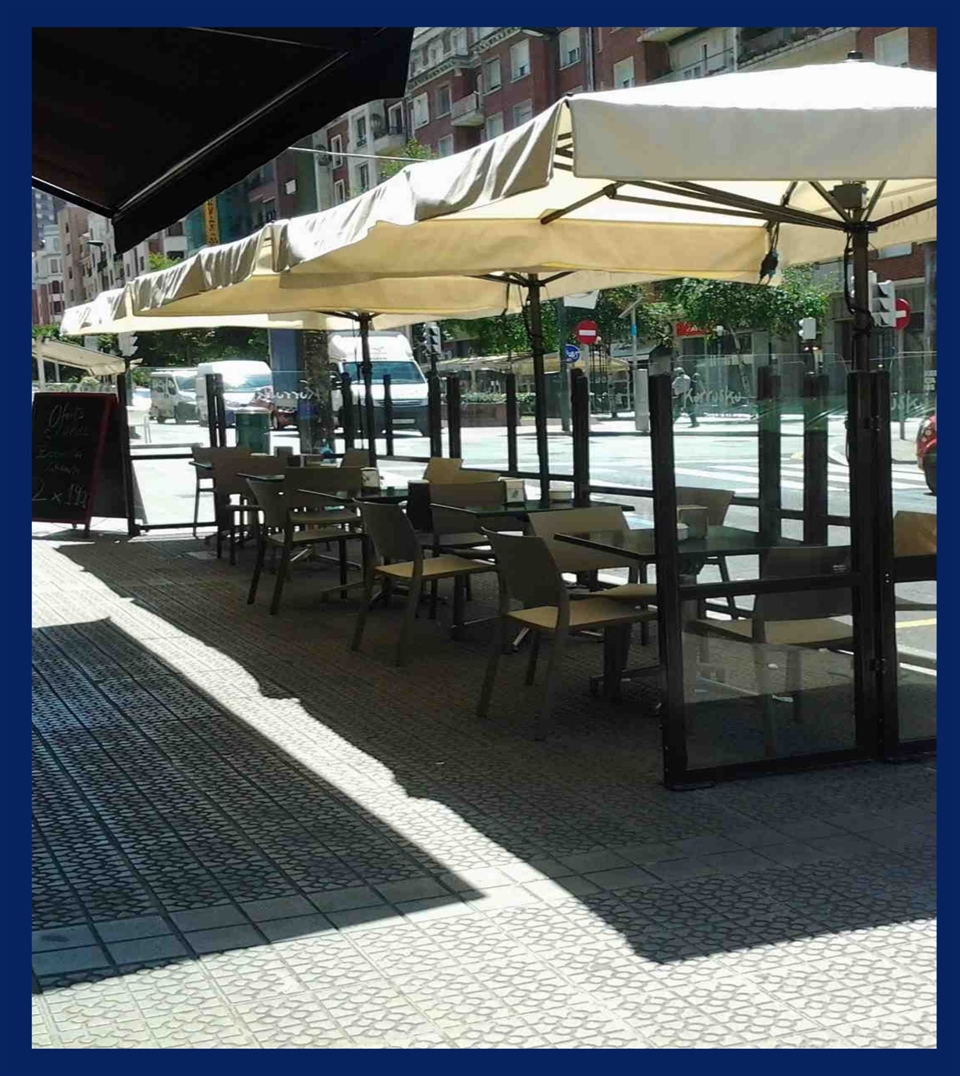 small beige umbrellas with a center pole on a streetside restaurant patio providing shade