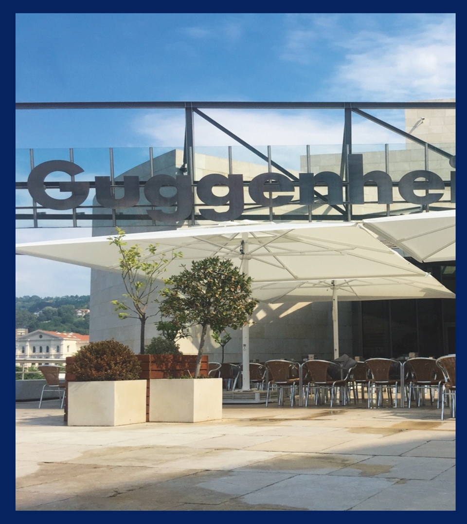 modern white patio umbrellas with a center pole sitting on the exterior grounds of an office buildin