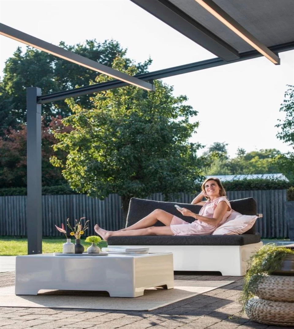 Woman relaxing under a modern pvc pergola in backyard. 