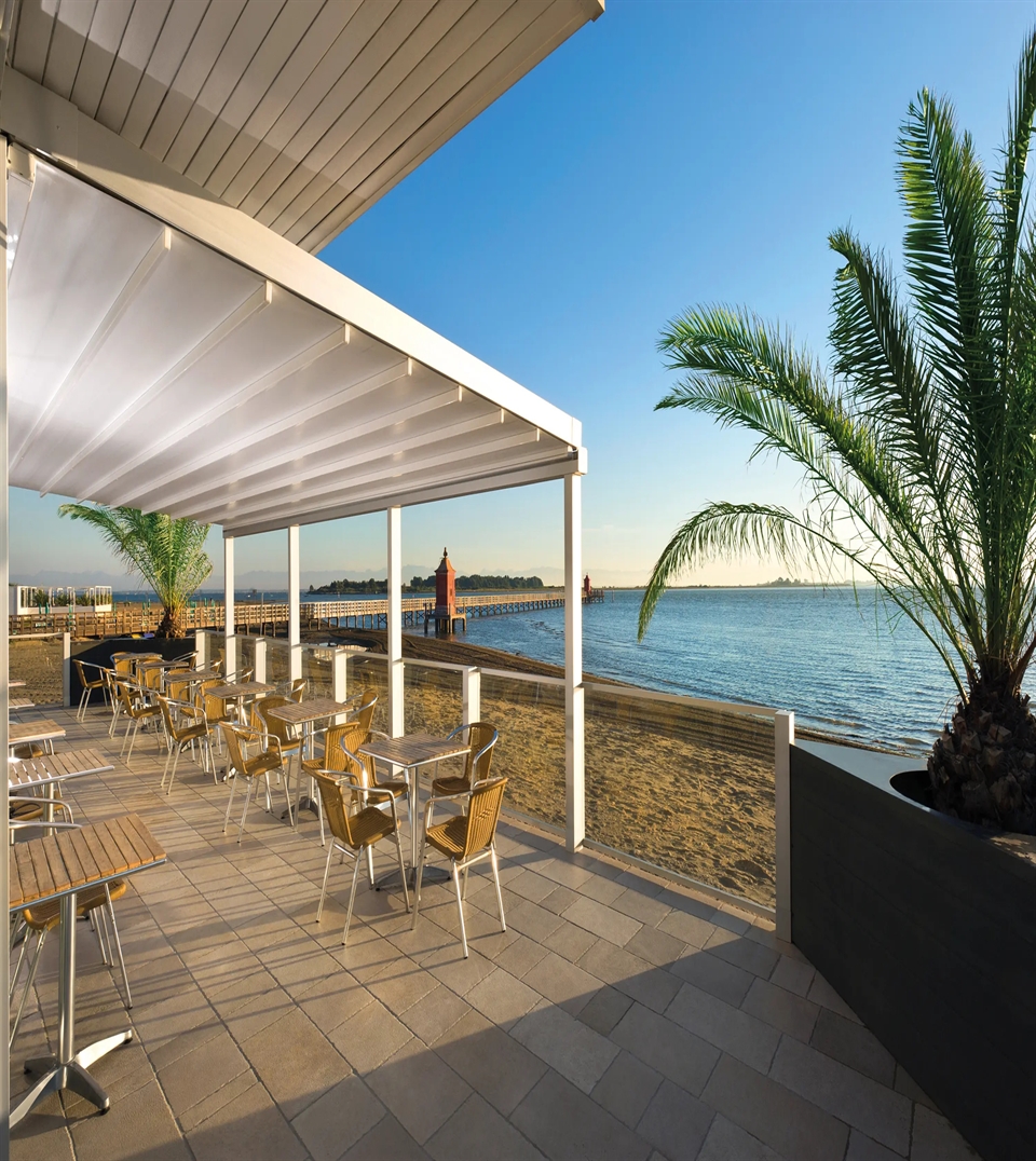 Classic sloped fabric pergola by Pratic with elegant white canvas and LED lights.