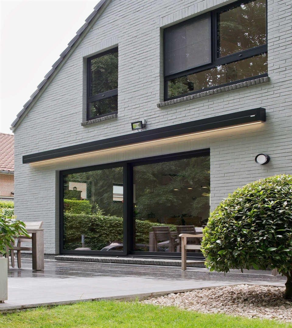 Modern home with sleek retractable awning and integrated LED lighting above a glass patio door.