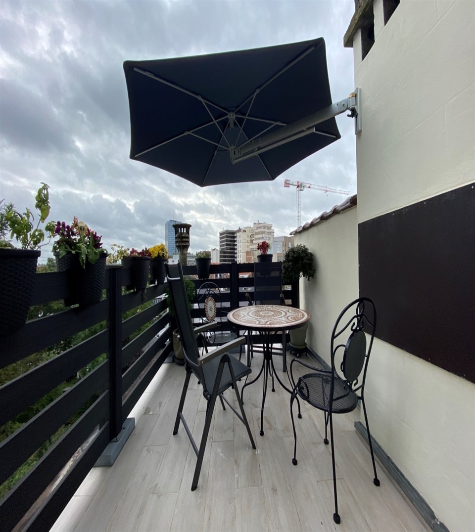 Prostor P3 wall-mounted umbrella with an extended telescopic arm over a patio table.