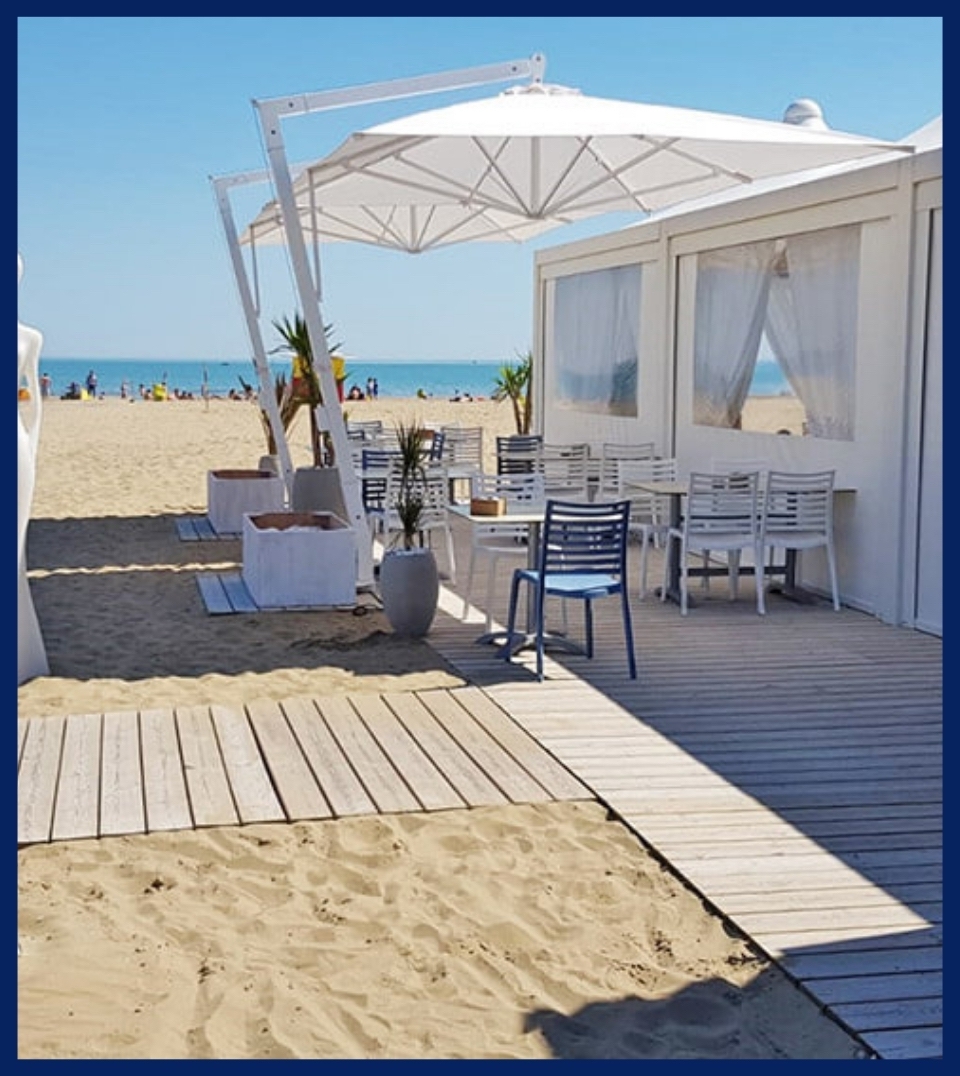 a modern sleek white umbrella on the patio of a beachside restaurant patio