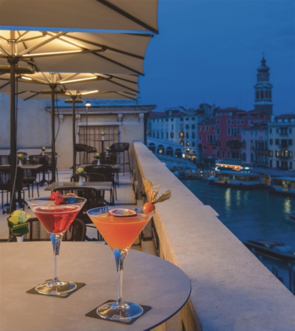Row of white Gaggio Professional umbrellas providing shade for an outdoor cafe.