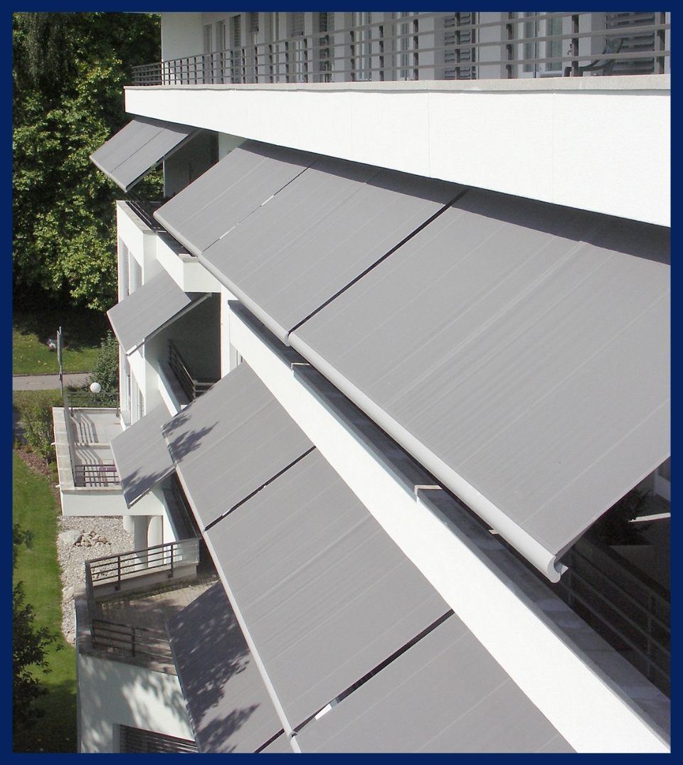 a series of grey awnings on an apartment building attached to the facade of each unit patio