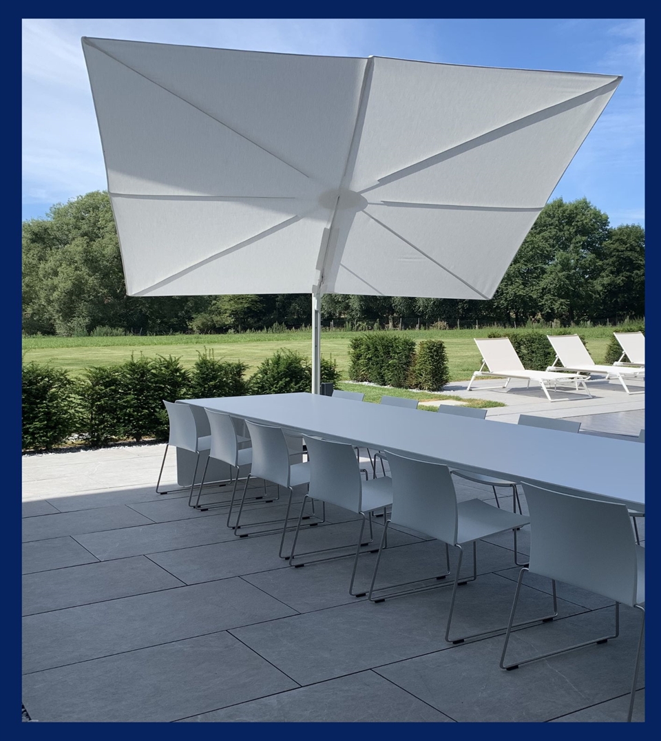 Modern white umbrella covering an outdoor dining table that is white