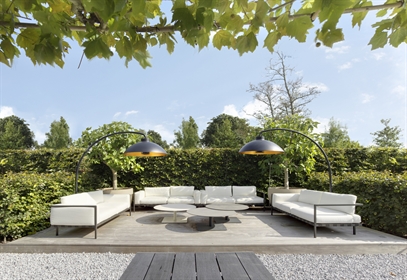 Outdoor lounge with two black Heatsail Dome lamps and white sofas on a wood