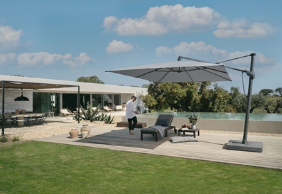 A white outdoor umbrella with grey fixings in the yard of a private home
