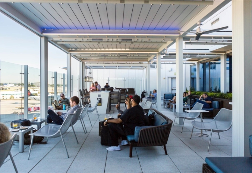 Pergola at an airport with people sitting looking out at planes