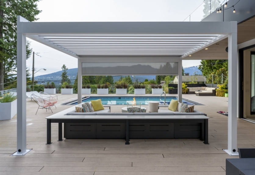white louvred pergola on a deck with a grey screen overlooking mountains